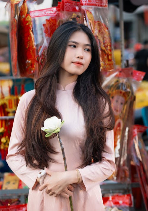 A woman in a pink dress holding a flower