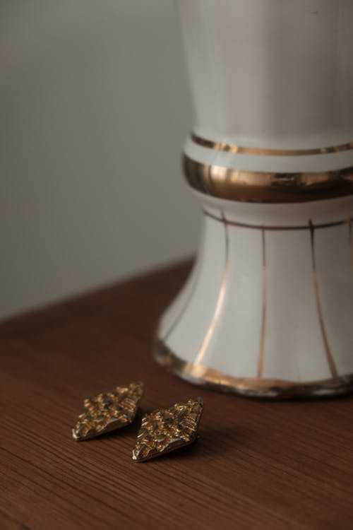 Golden Earrings Next to a Vase 