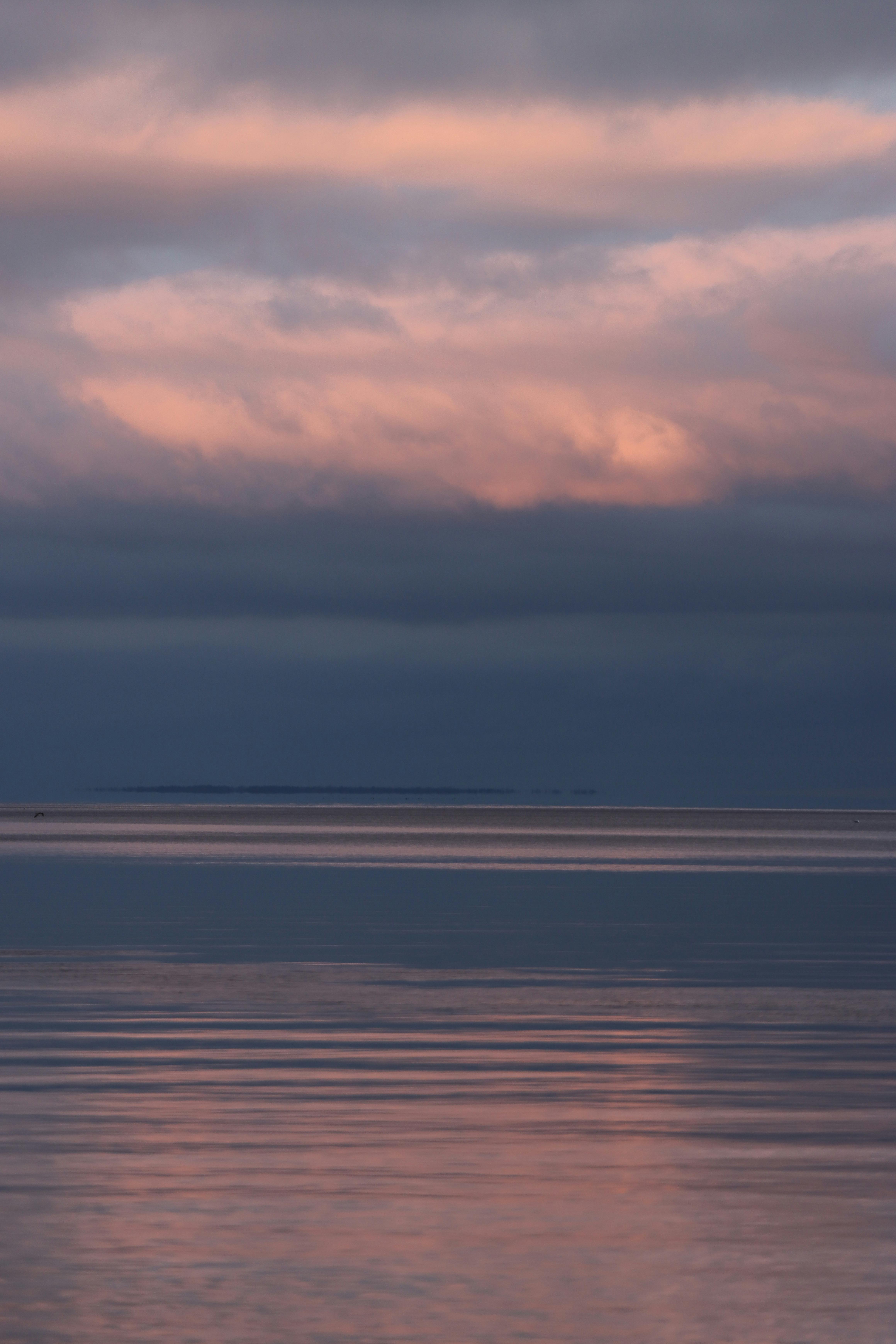 Peaceful sunset sky over lake in Jönköping, Sweden with soft reflections and dramatic clouds.