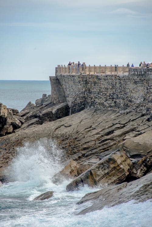 People on Stone Wall on Sea Coast