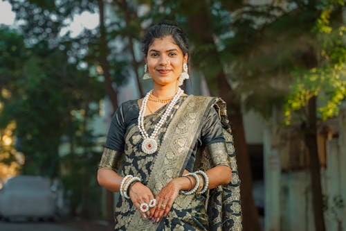 A woman in a black sari and gold jewelry