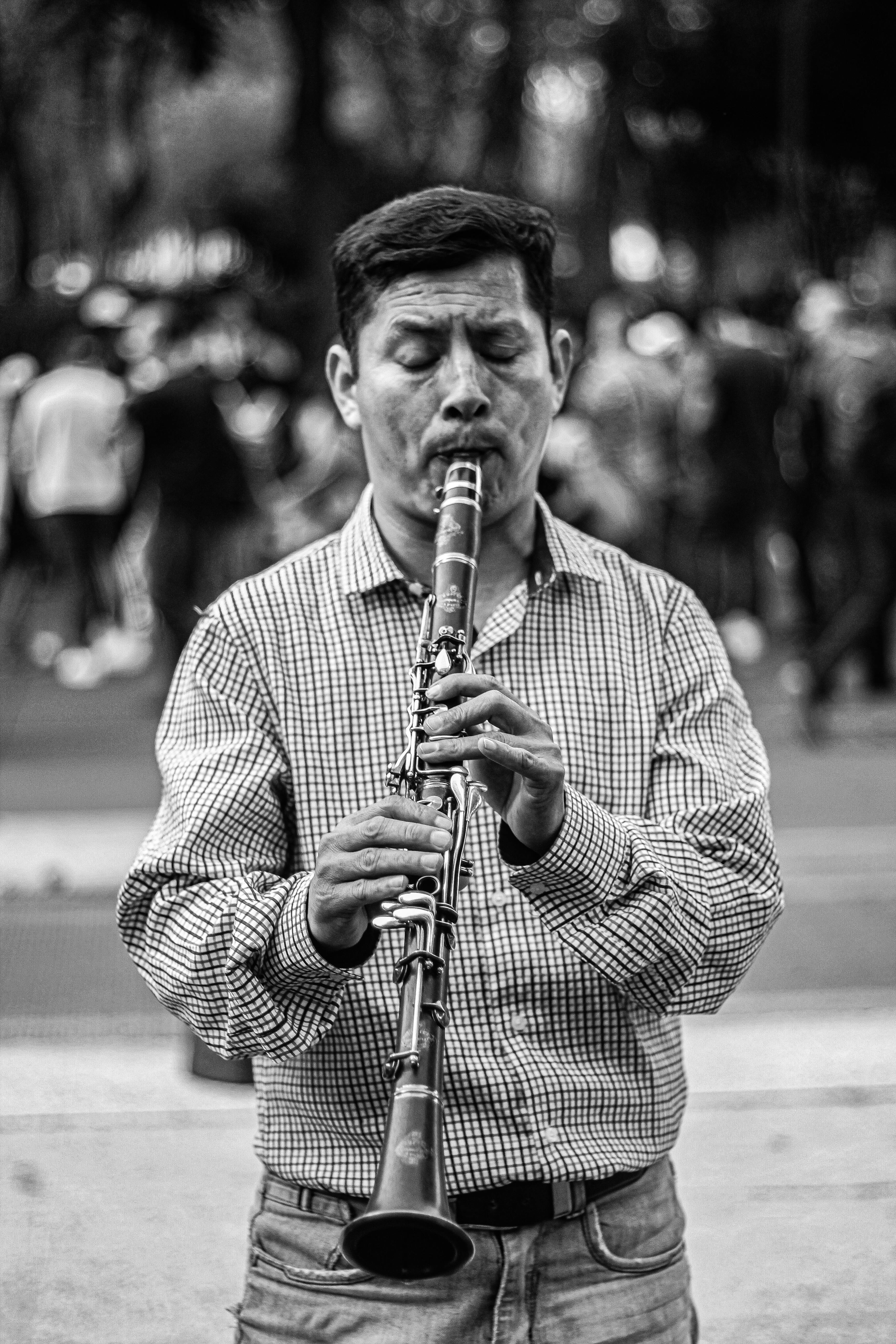 A black and white portrait of a street musician passionately playing the clarinet in Mexico City.