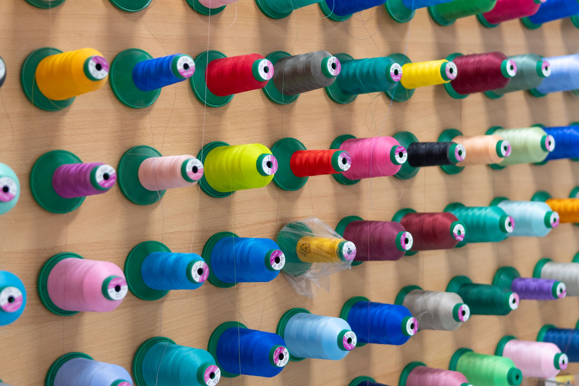 Close-up of Colorful Thread Spools on a Wall · Free Stock Photo
