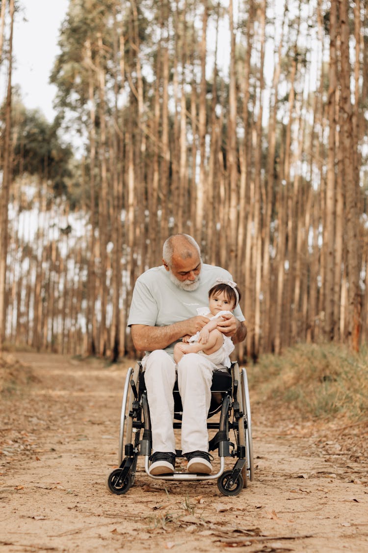 Man In Wheelchair Holding Child