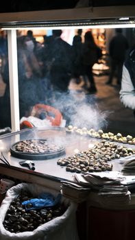 Street vendors offering roasted chestnuts in Istanbul at night under city lights.
