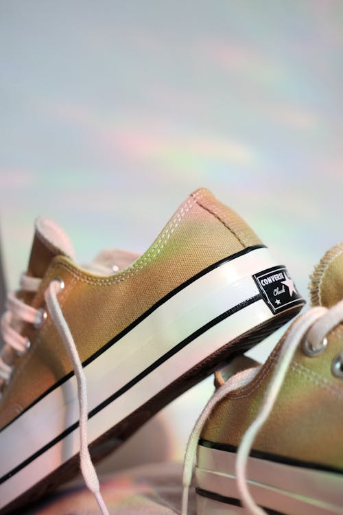 A pair of gold sneakers with a rainbow background