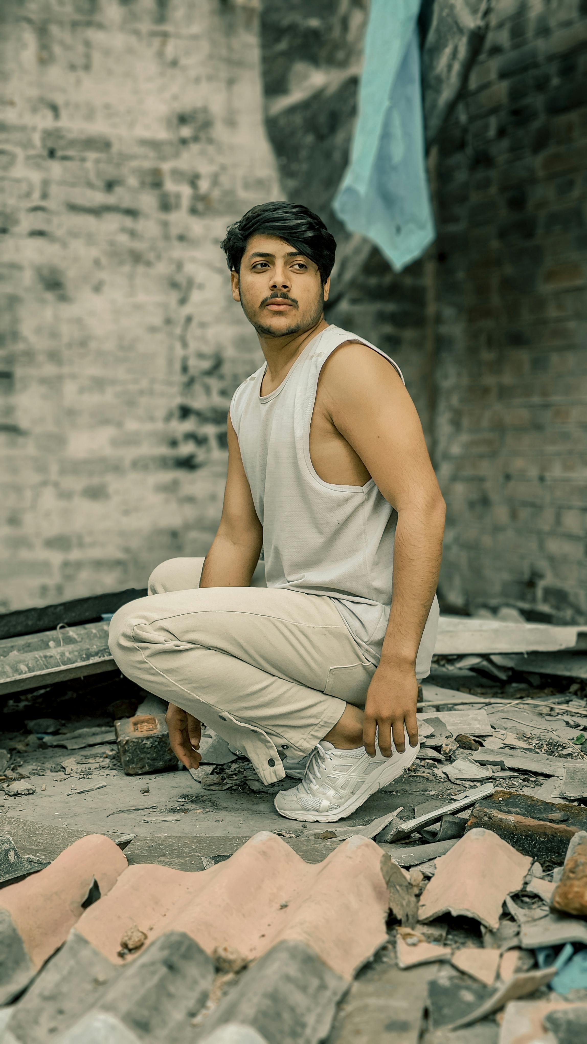 A fashionable man posing amidst the rubble of an abandoned building, exuding style and strength.