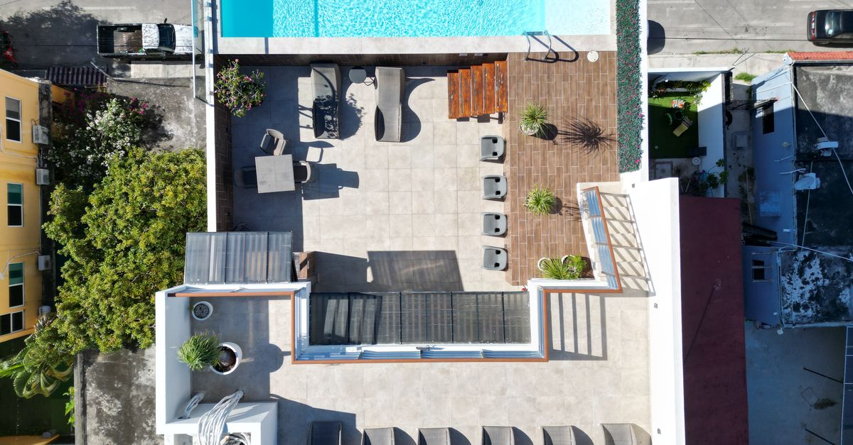 Drone shot of a luxury rooftop terrace with a pool in Playa del Carmen, showcasing modern architecture.