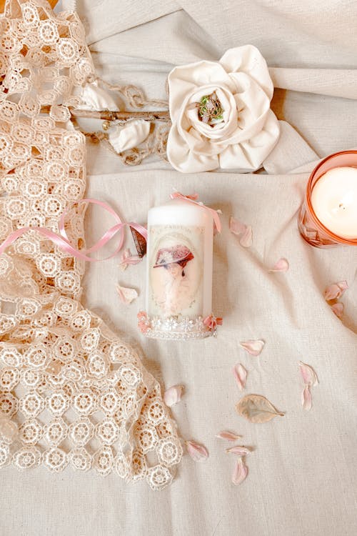 A candle and a pink flower on a table