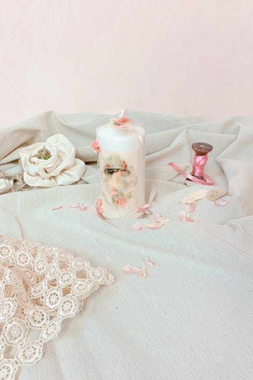 A candle and a pink flower on a bed