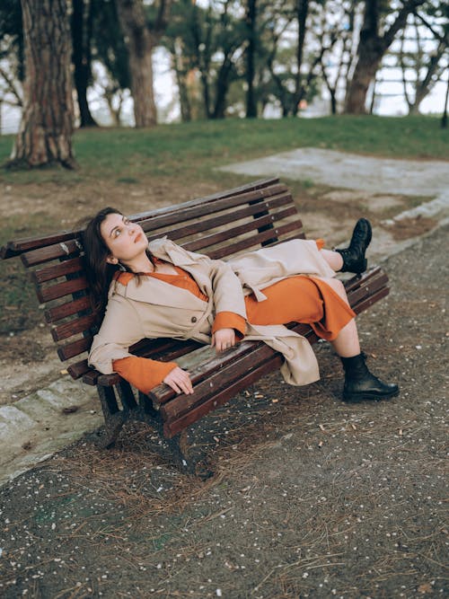 Woman in Trench Lying Down on Bench at Park
