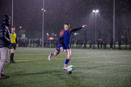 Player Kicking Rugby Ball in Rain