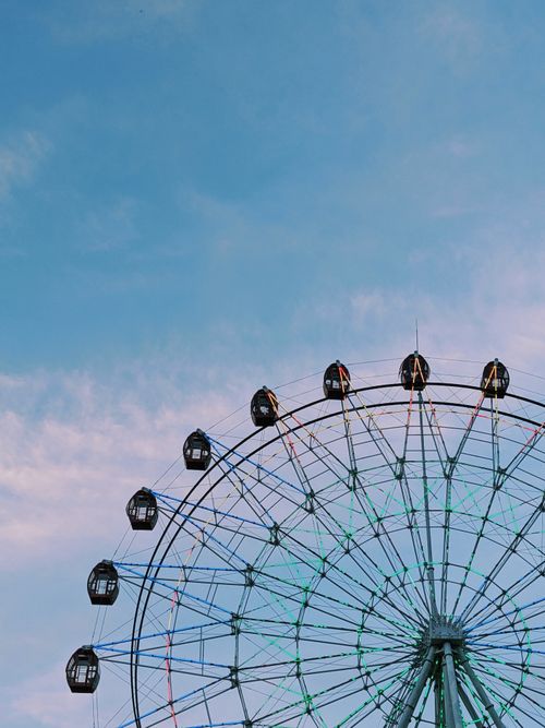 Free A vibrant Ferris wheel set against a clear blue sky, perfect for themes of fun and travel. Stock Photo