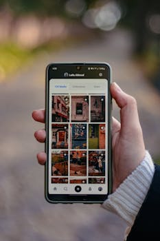Person holding smartphone displaying an online photo gallery app outdoors.