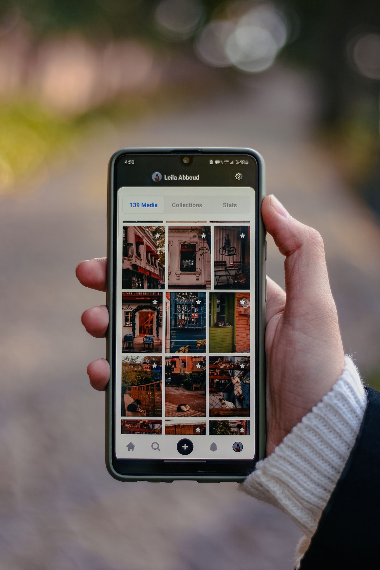 Person holding a smartphone displaying a photo gallery app, the kind of scrolling that precedes a reblog