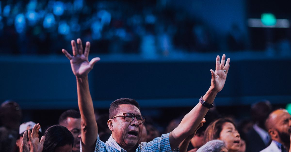 Crowd reacting emotionally with hands raised during a sermon