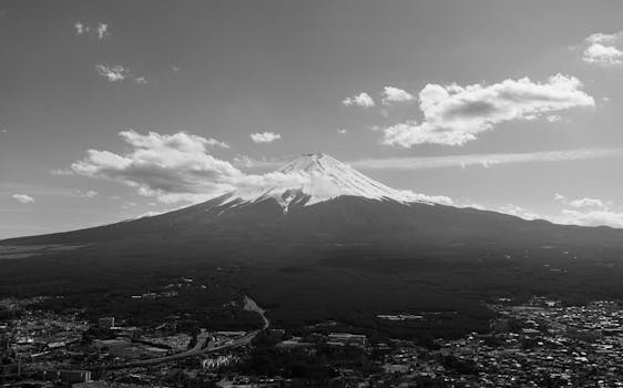 Dramatic aerial black and white capture of Mount Fuji under a clouded sky.