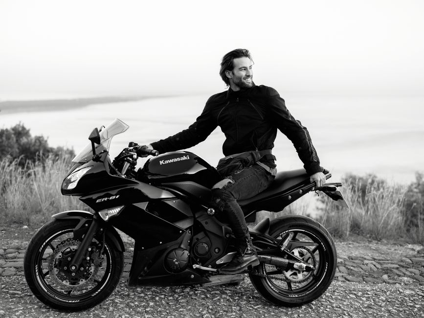 Man on a black Kawasaki motorcycle enjoying a scenic view in Lisbon.