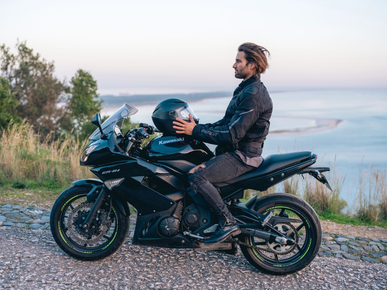 Motociclista sentado na sua mota junto à costa de Lisboa