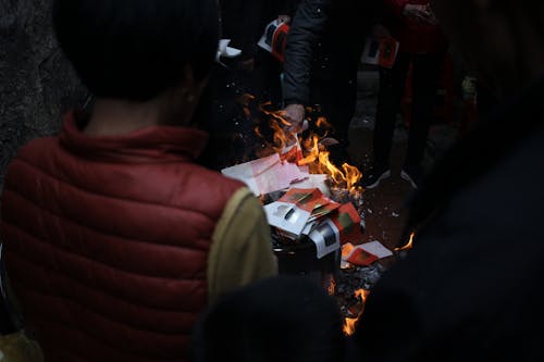 People are gathered around a fire with a box of books