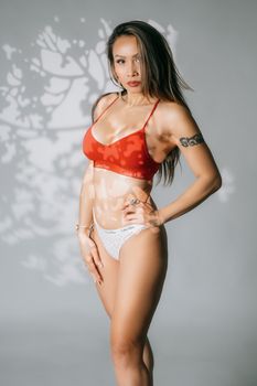 Stylish portrait of a woman wearing red bra and white underwear in studio setting.