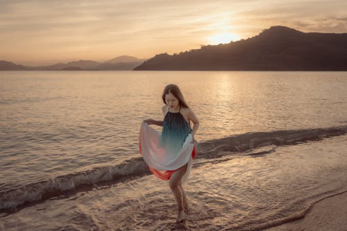 A girl standing on the beach at sunset