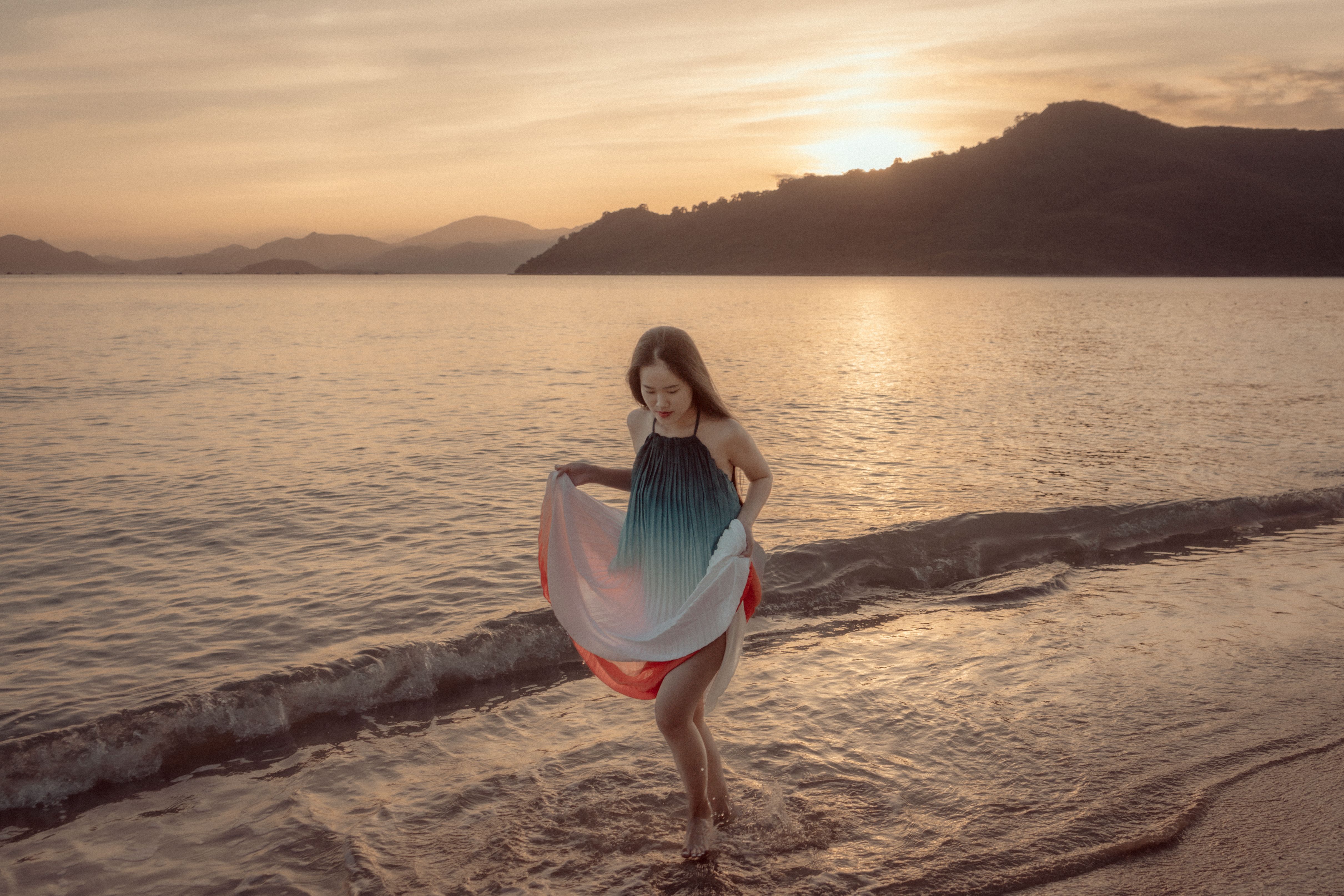 Woman in Sundress Walking on Sea Shore at Sunset · Free Stock Photo