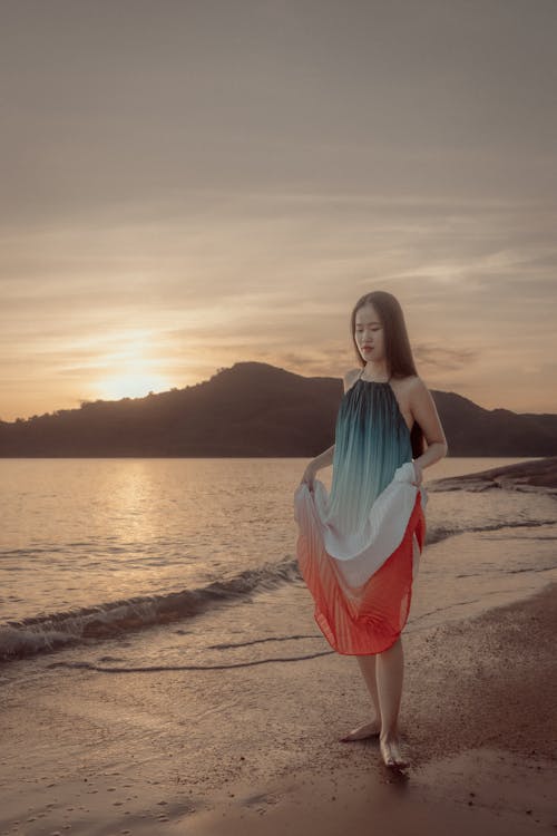 Woman in Colorful Dress Posing on a Beach at Sunset