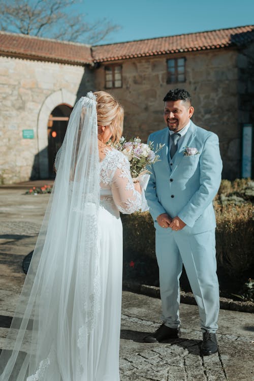 A bride and groom standing in front of a stone building