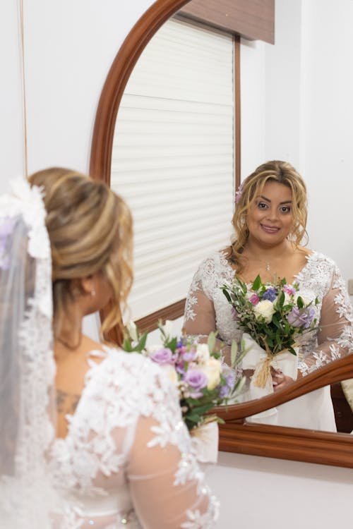 Bride looking in mirror at her wedding dress