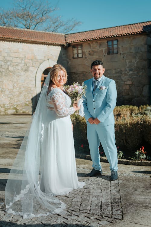 A bride and groom standing in front of a stone building