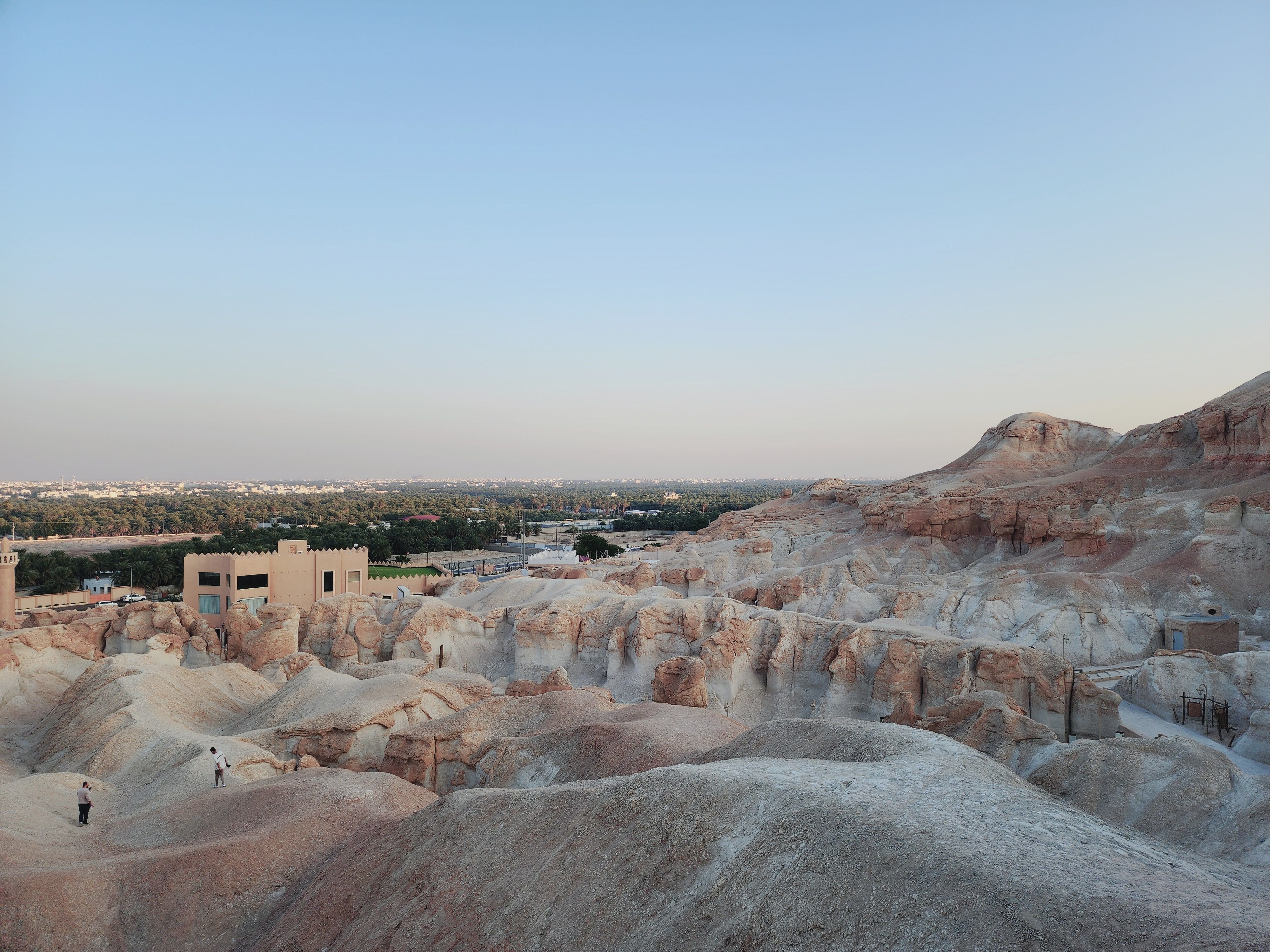 Eroded rock formations and caves at Al Hofuf with the green Al-Ahsa oasis beyond