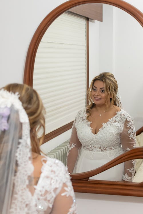 Bride in Wedding Dress Standing by Mirror