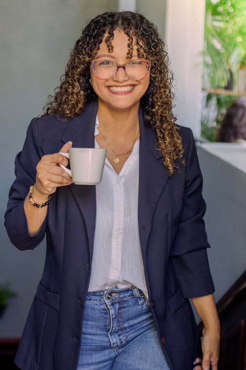 A woman in glasses holding a coffee cup