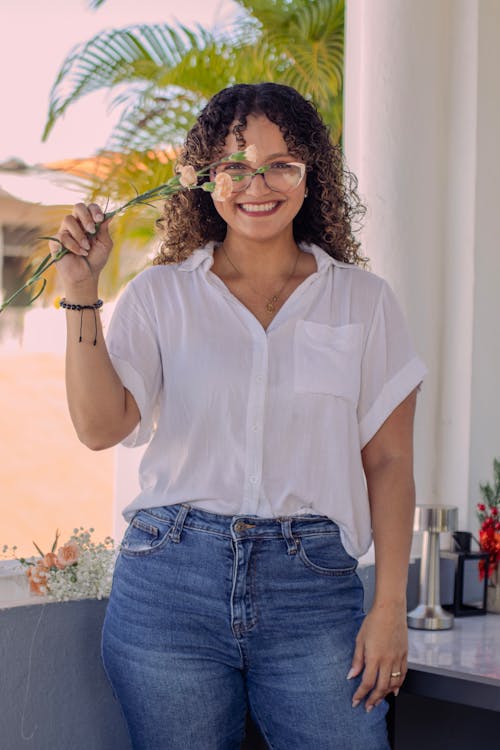 A woman in glasses and jeans holding a glass of wine