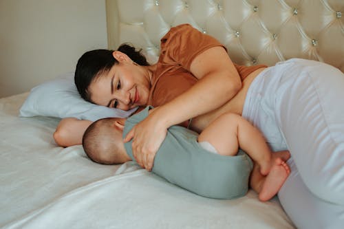 Smiling Woman Lying in Bed with Her Baby
