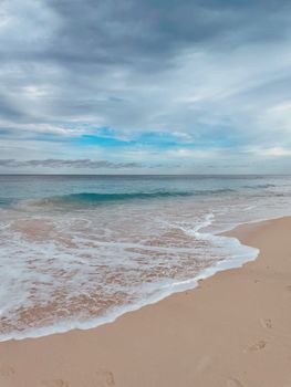 Peaceful beach scene with gentle waves and a cloudy sky, perfect for travel or relaxation themes.