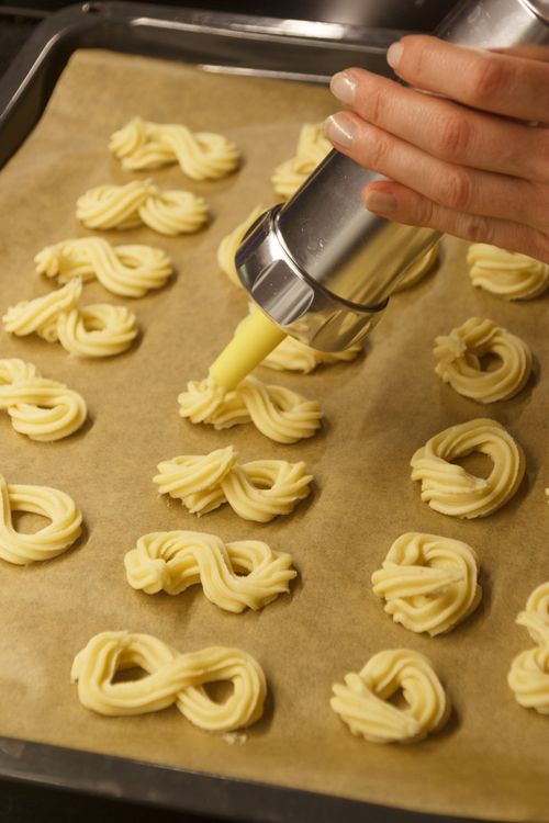 Free Close-up of a hand using a cookie press to make homemade biscuits on a baking tray. Stock Photo