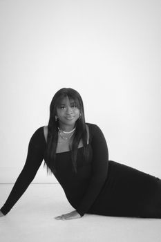 Black and white portrait of a woman in a stylish dress, exuding elegance and confidence.