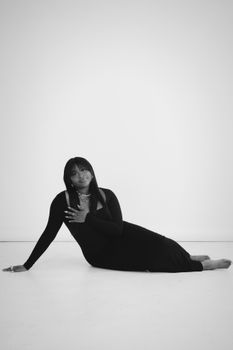 Beautiful black and white studio shot of a woman in a long dress, posing elegantly.