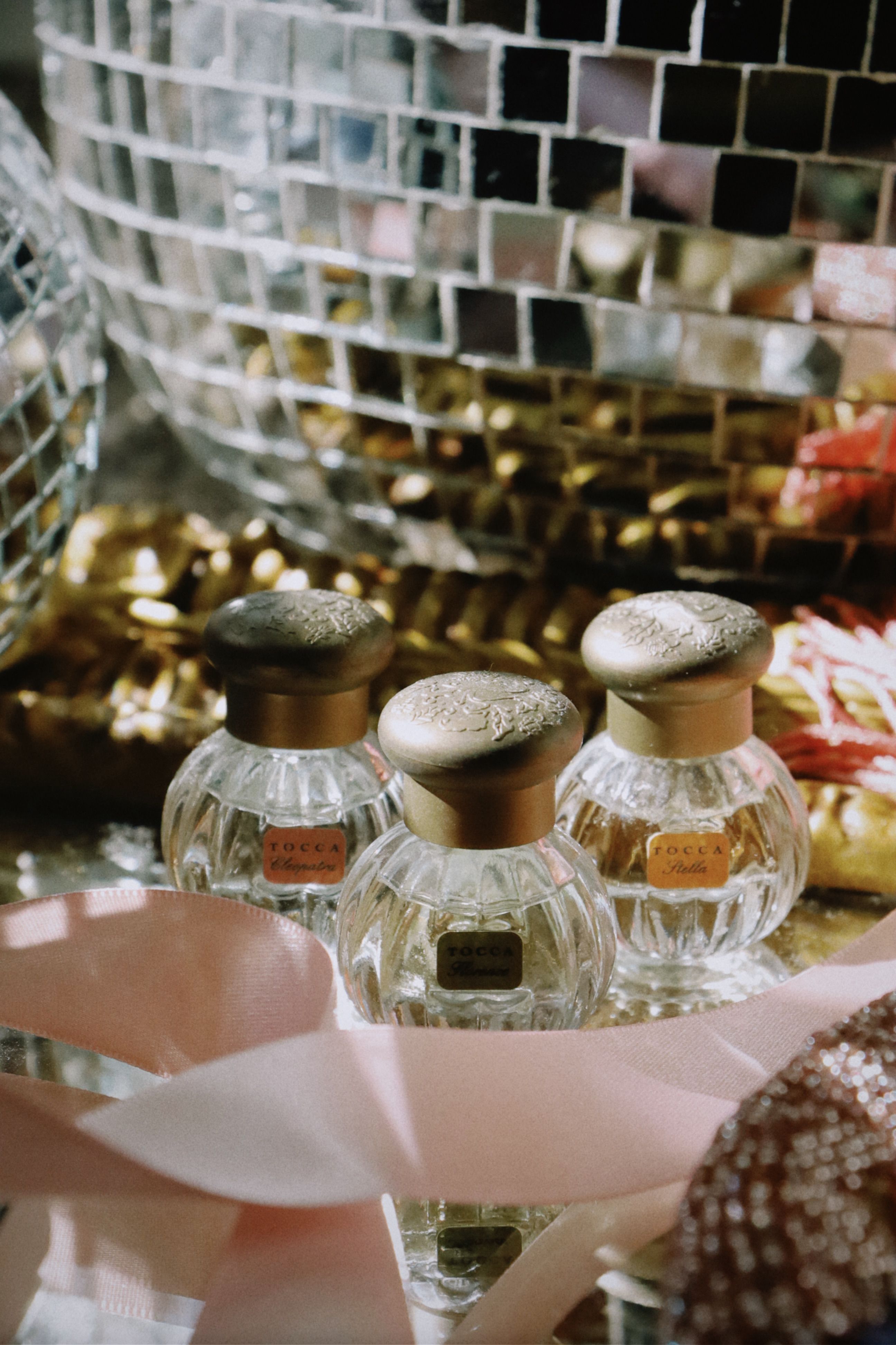 Elegant arrangement of perfume bottles with a party-themed background featuring a disco ball.