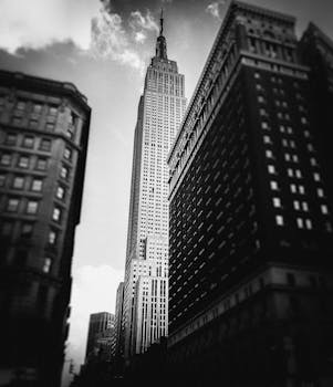 Dramatic black and white view of the Empire State Building amidst New York City skyscrapers.