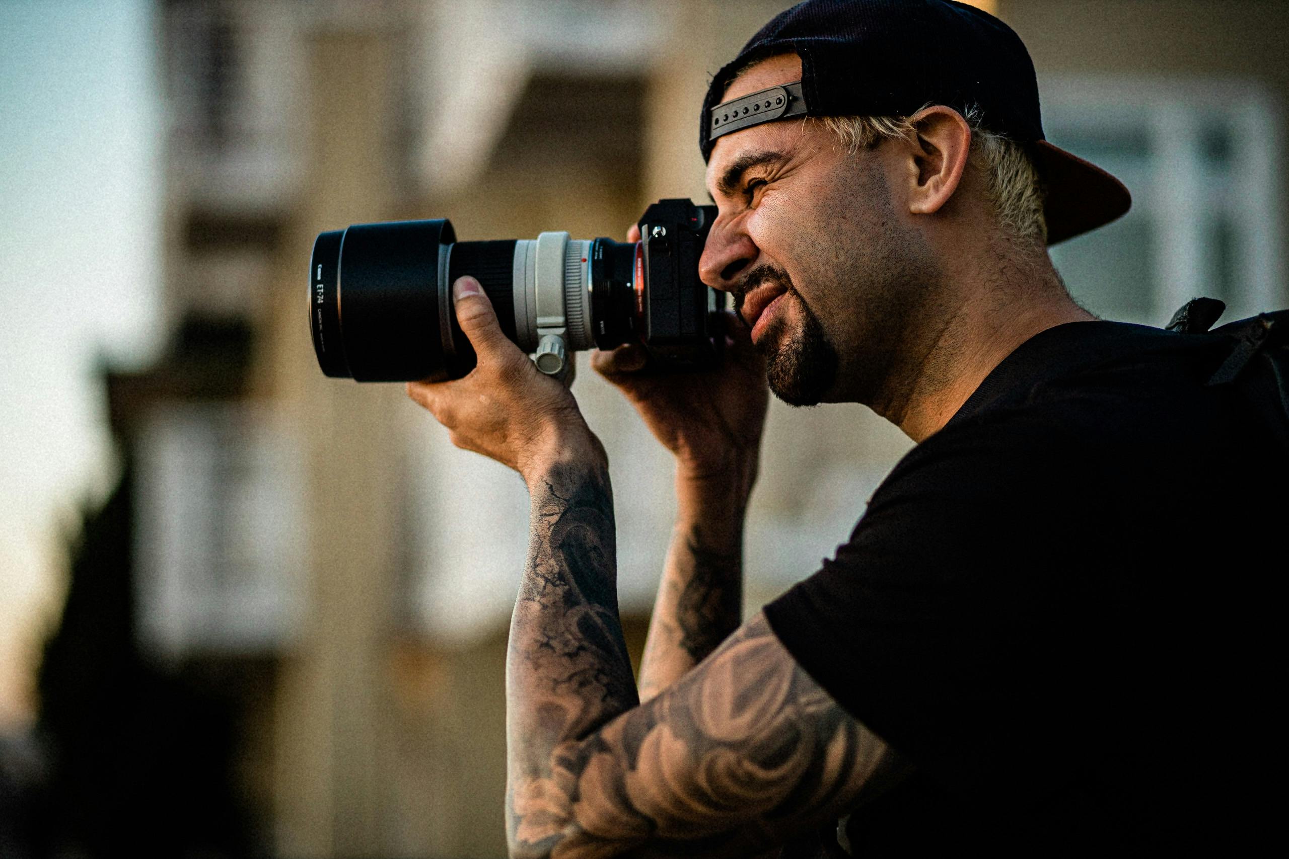 Portrait of a tattooed photographer capturing images during sunset at Hermosa Beach.