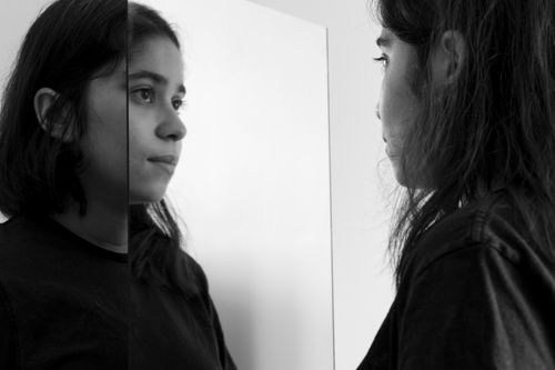 Young woman looking at herself in the mirror, black and white