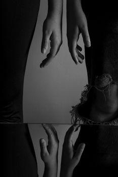 Artistic black and white photo with hands and reflection.