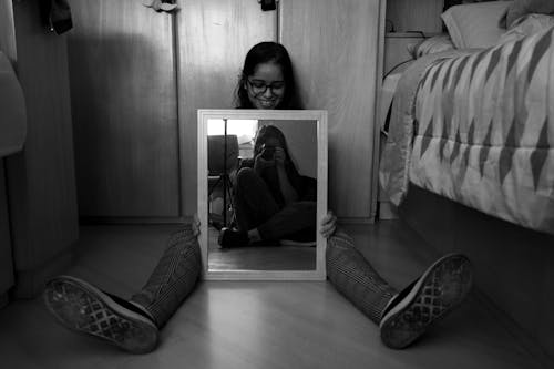 Smiling Woman Sitting with Mirror on Floor in Black and White