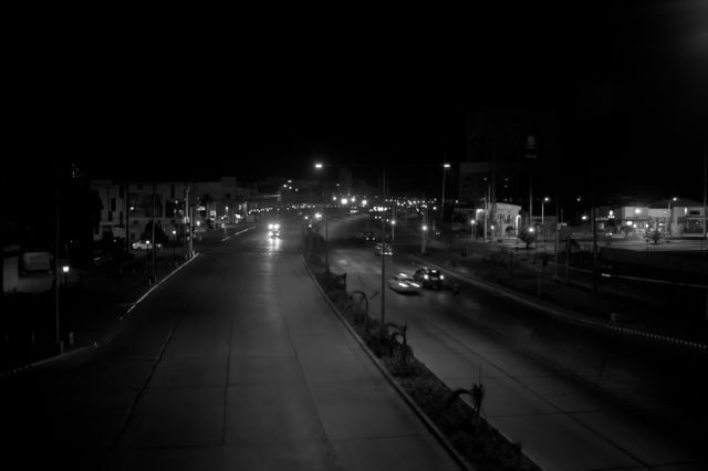 An empty road at night under scattered street lights, photo by Jero Belarmino on Pexels