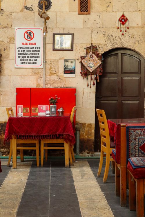 Free Cozy Turkish restaurant interior with decorative walls and red-themed table settings. Stock Photo