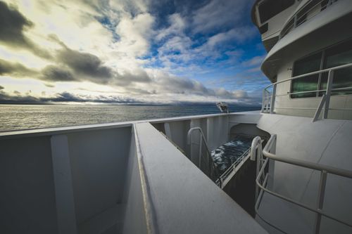 Free A modern ship sailing under a dramatic sky on a tranquil sea, suggesting travel and adventure. Stock Photo