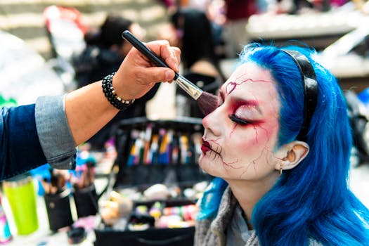 Artist applying intricate makeup design on a woman with blue hair.